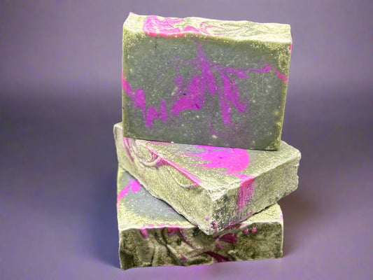 Three bars of soap with gray and pink marbled pattern on a black background