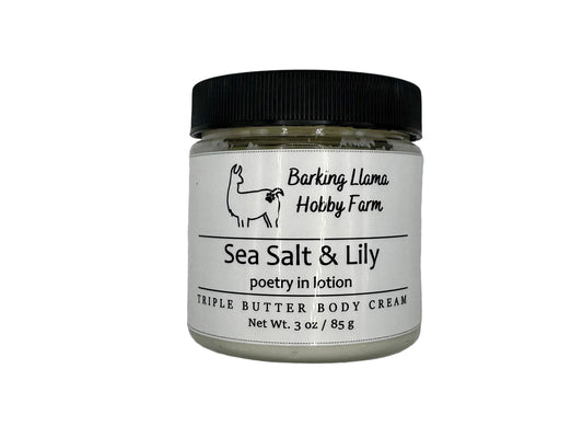 Clear jar with a black lid with white body cream inside. The label has a picture of a llama with the title of the lotion on the front.